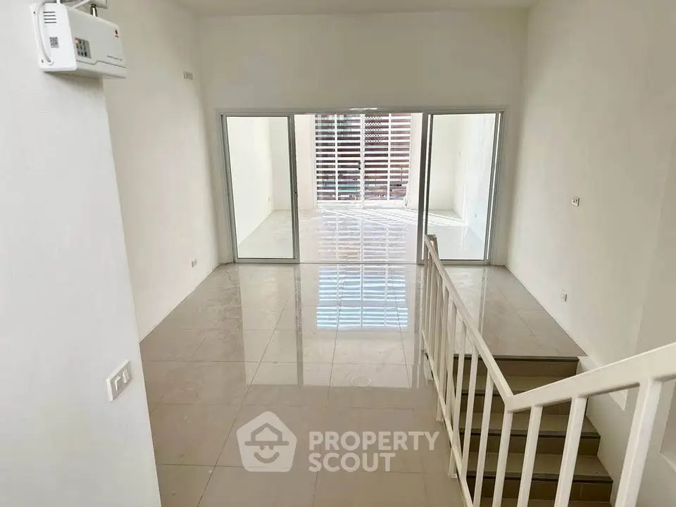 Spacious modern living room with glossy tiled floors and large sliding glass doors leading to a bright balcony.