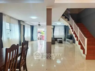 Spacious open-plan living area with elegant staircase and dining set, perfect for family gatherings.