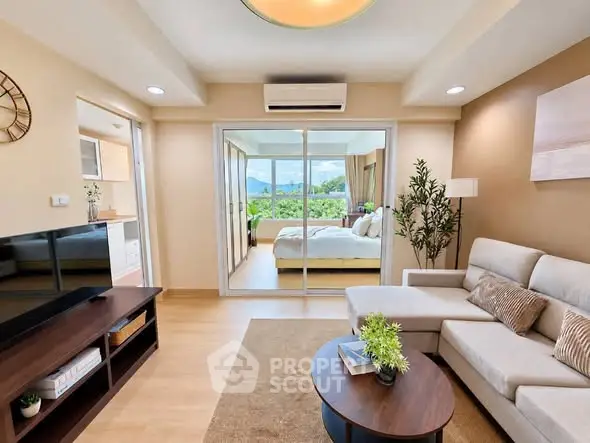 Modern living room with open view to bedroom, featuring stylish decor and natural light.