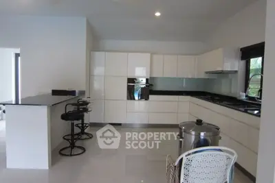 Modern kitchen with sleek white cabinetry and breakfast bar seating