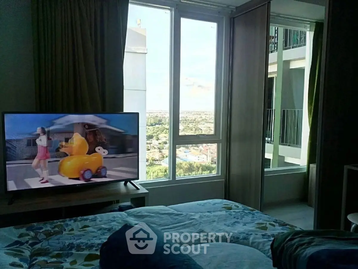 Cozy bedroom with large windows offering a stunning city view, featuring a modern TV setup.