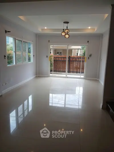 Spacious living room with large windows and modern lighting, perfect for family gatherings.