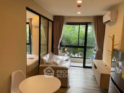 Modern living room with large windows and greenery view, featuring cozy furniture and stylish decor.