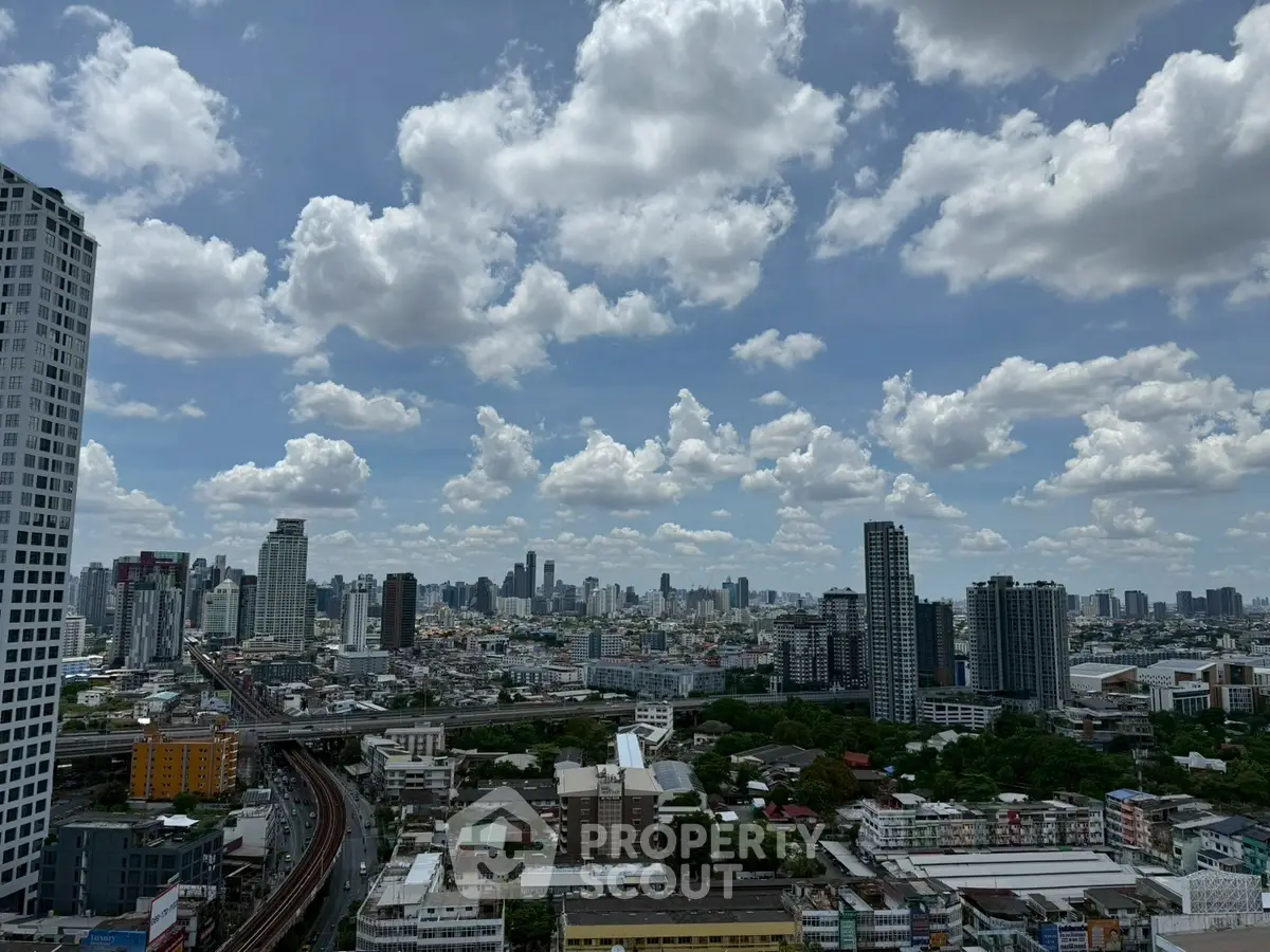 Stunning cityscape view from high-rise building with clear blue sky and clouds.