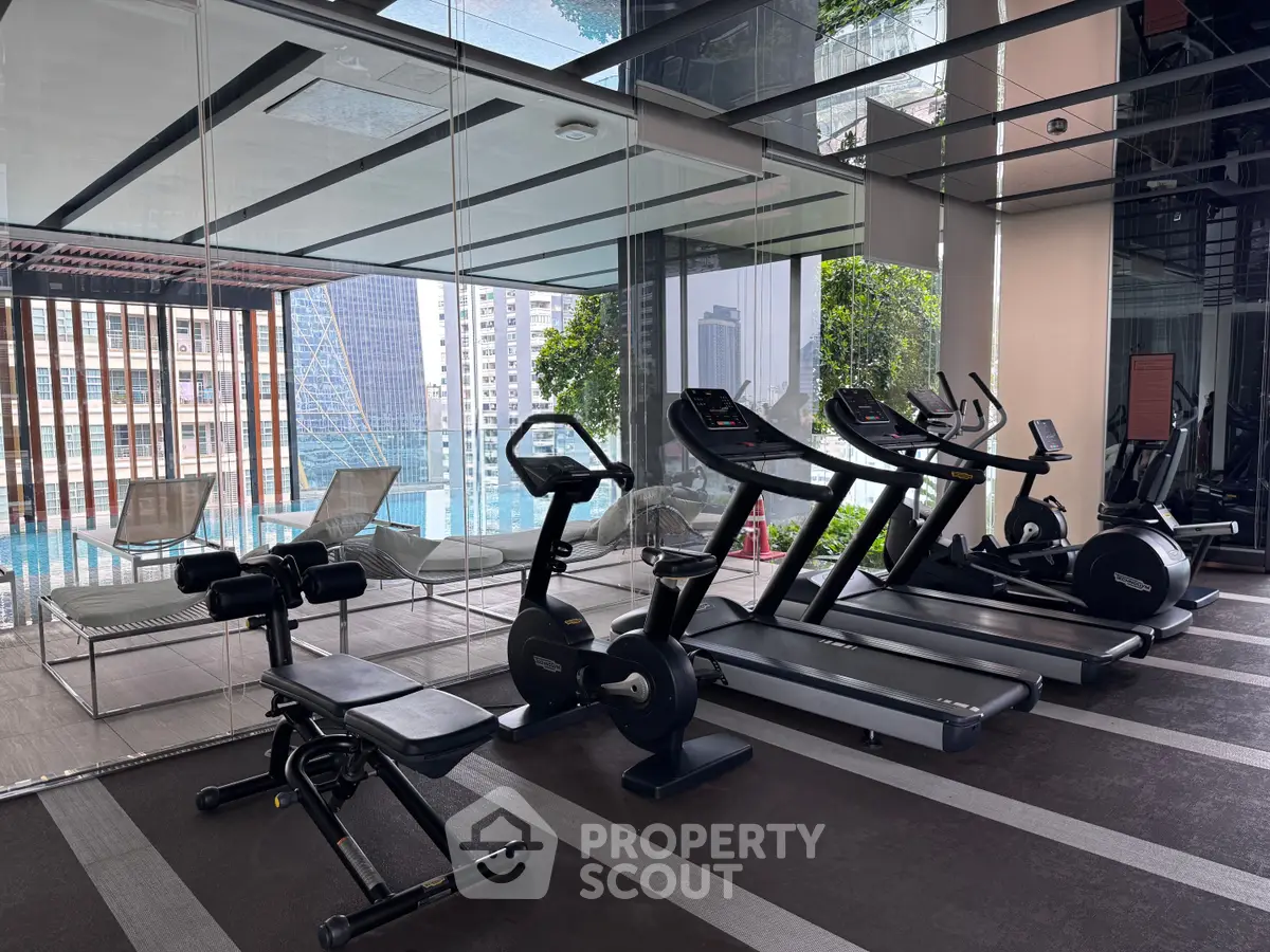 Luxurious gym with modern equipment and pool view in high-rise building