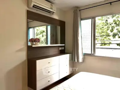 Bright bedroom with large window and modern dresser, featuring air conditioning and elegant decor.