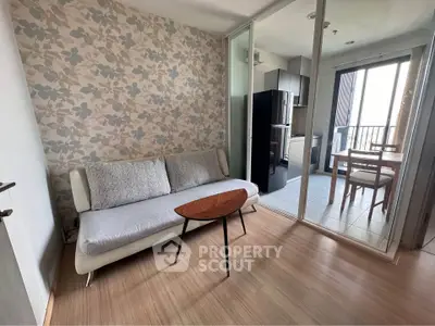Modern living room with floral wallpaper and cozy sofa, adjacent to a dining area with balcony view.
