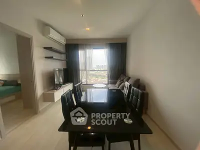 Modern living room with dining area and city view, featuring sleek furniture and natural light.