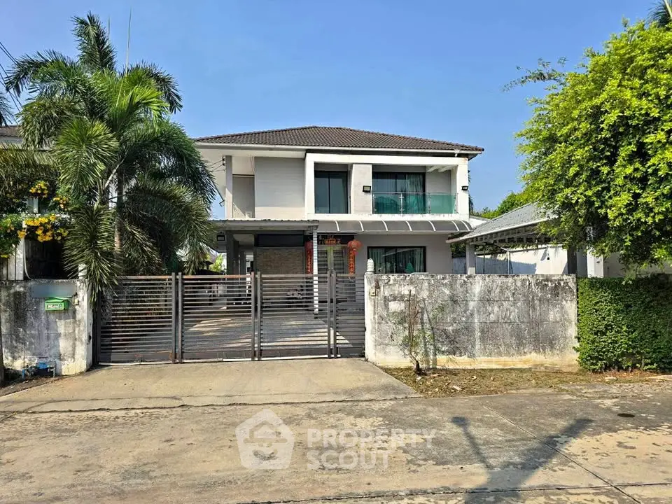 Modern two-story house with gated entrance and lush greenery, perfect for family living.