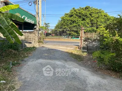 Gated entrance to a property with lush greenery and clear blue sky.