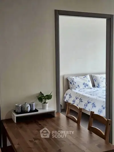 Cozy bedroom with floral bedding and adjacent dining area, perfect for modern living.