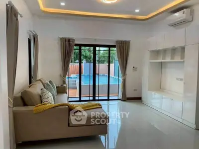 Modern living room with pool view, featuring sleek furniture and large windows for natural light.