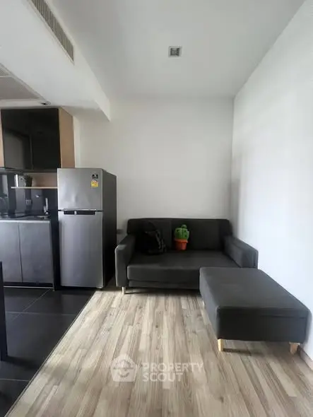 Modern living room with sleek kitchen and stylish gray sofa, perfect for urban living.