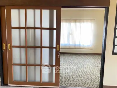 Spacious room with sliding glass doors and patterned carpet, ideal for versatile living space.