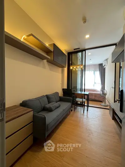 Modern living room with sleek furniture and view into cozy bedroom