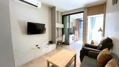 Modern living room with sleek furniture and large TV, leading to a bright balcony with a view.