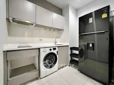 Modern kitchen with sleek appliances and washing machine in compact layout.