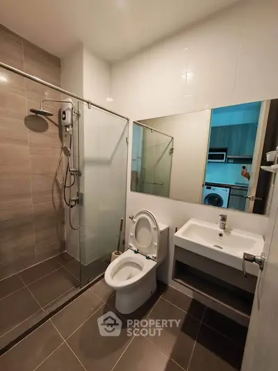 Modern bathroom with glass shower and sleek fixtures in contemporary apartment.