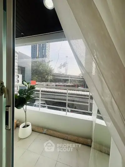 Charming balcony with city view and elegant curtain, perfect for relaxation.