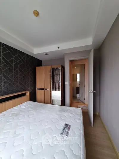 Modern bedroom with stylish decor and wooden furniture, featuring a comfortable bed and ample natural light.