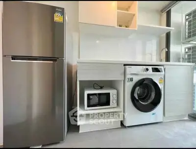 Modern kitchen with sleek appliances including fridge, washing machine, and microwave in compact layout.