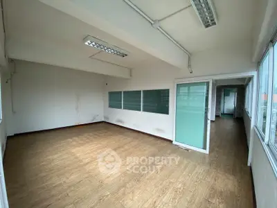 Spacious office space with wooden flooring and large windows for natural light.