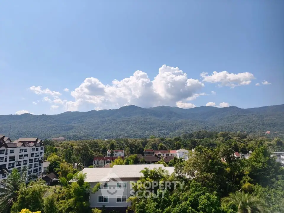 Stunning mountain view from a high-rise apartment, showcasing lush greenery and clear blue skies.