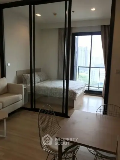 Modern apartment with glass partitioned bedroom and city view balcony.