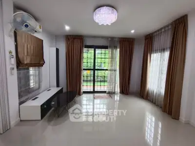 Spacious living room with elegant chandelier and large windows for natural light.