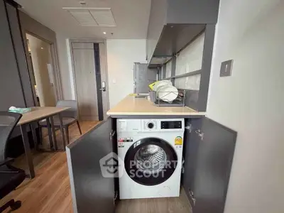 Modern apartment interior with built-in washing machine and sleek cabinetry.