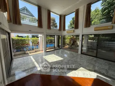 Spacious living room with large windows and marble flooring, offering a bright and airy atmosphere.