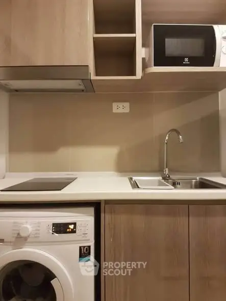 Modern kitchen with washing machine and microwave in compact layout