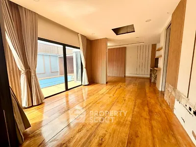 Spacious living room with wooden flooring and poolside view
