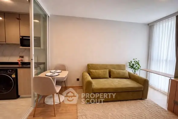 Modern living room with cozy green sofa and dining area in open layout apartment.