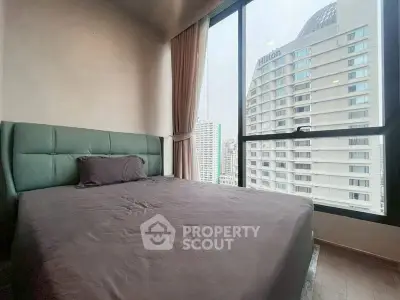 Modern bedroom with large window offering cityscape view, featuring a stylish bed and elegant curtains.