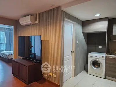 Modern apartment interior with TV, air conditioning, and washing machine in a cozy setting.