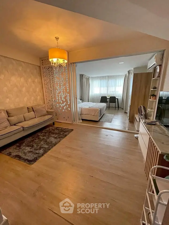 Modern open-plan living room with cozy seating and stylish bedroom divider.