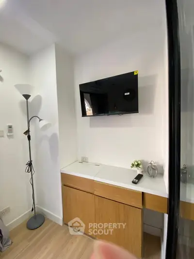 Modern living room corner with wall-mounted TV and sleek wooden cabinet