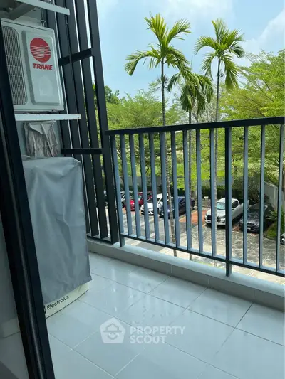 Charming balcony with lush greenery view and modern railing, perfect for relaxation.