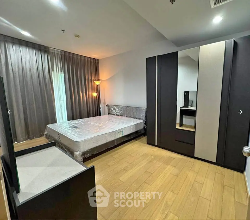 Spacious bedroom with modern furniture and large window for natural light.