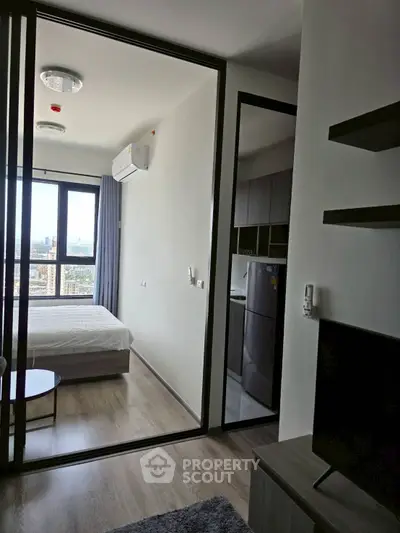 Modern apartment interior with bedroom and living area, featuring large windows and sleek design.