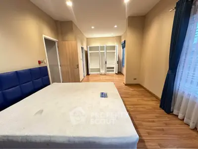 Spacious bedroom with wooden flooring and large windows for natural light.