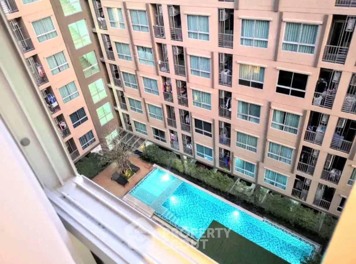 Stunning aerial view of modern apartment complex with pool and lush greenery, perfect for urban living.