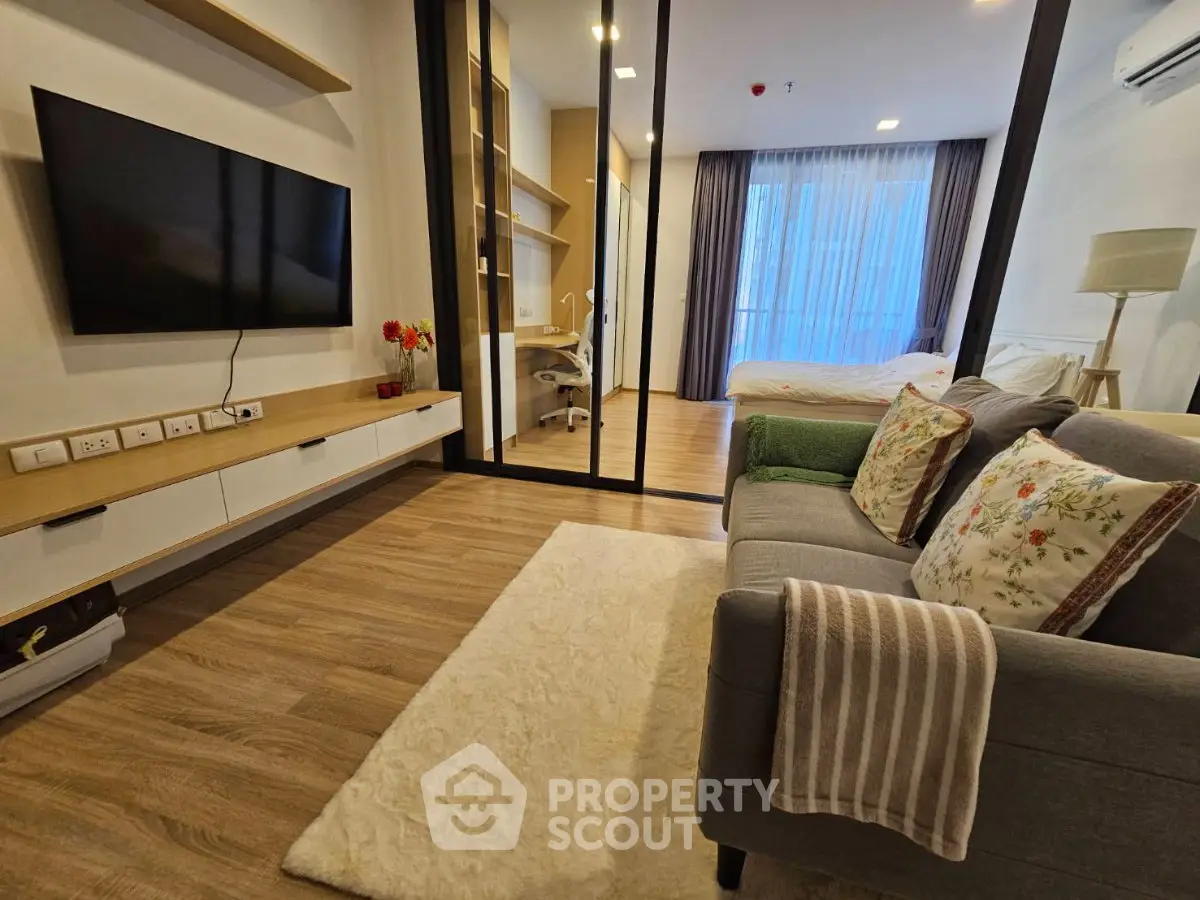Modern studio apartment with stylish living area and cozy bedroom, featuring sleek furniture and natural light.