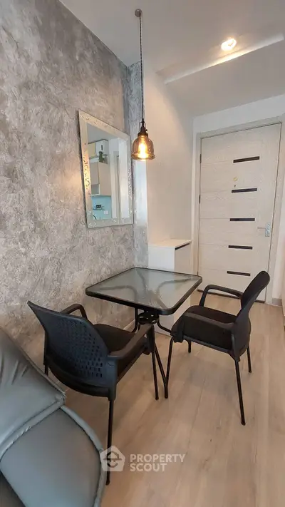 Modern living room with stylish decor and cozy seating area, featuring a glass table and pendant lighting.