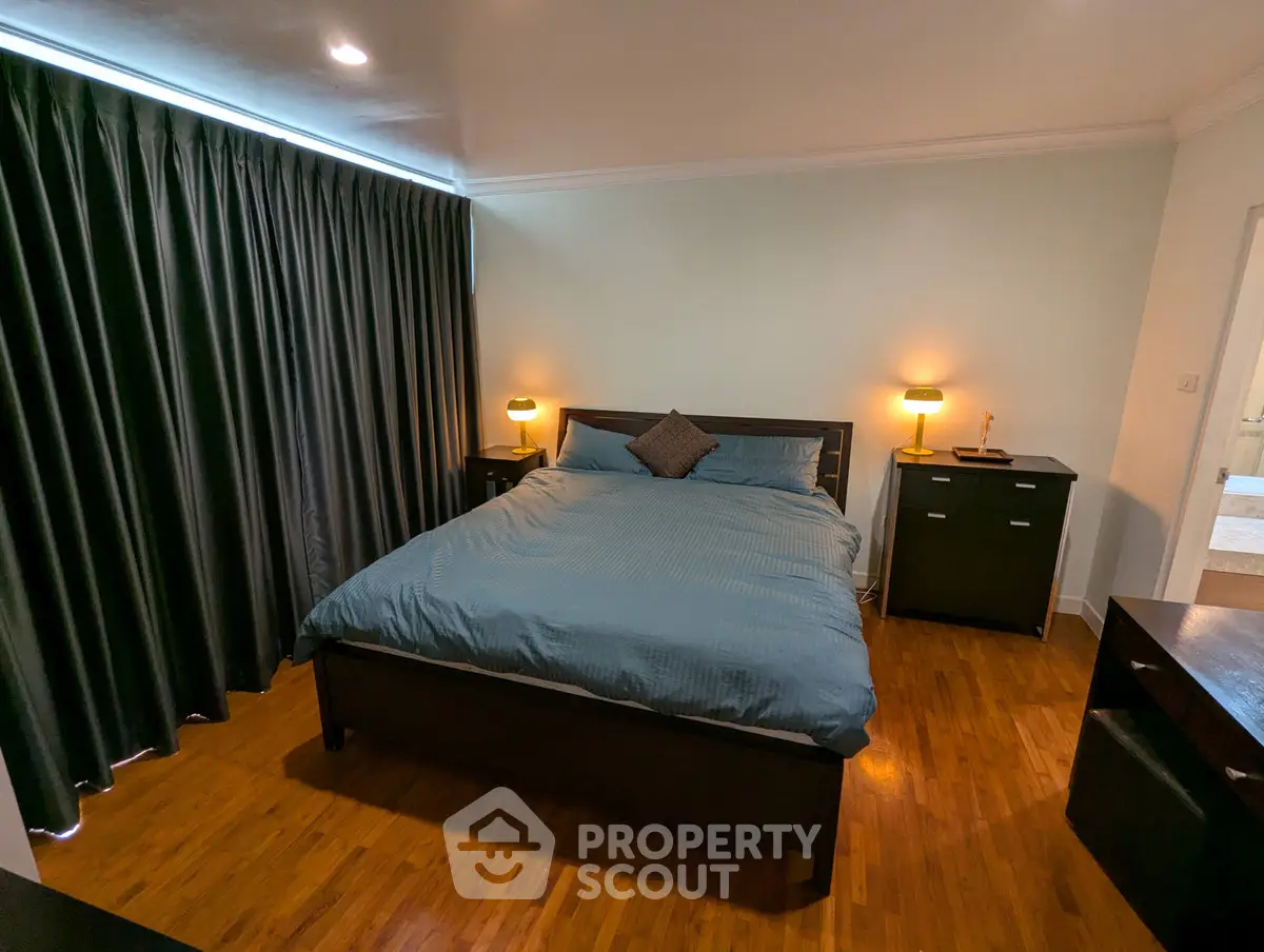 Spacious bedroom with elegant dark curtains and cozy lighting