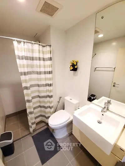 Modern bathroom with striped shower curtain and sleek fixtures in a contemporary apartment.