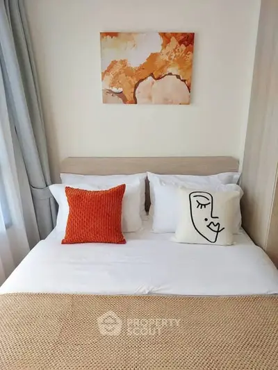 Cozy bedroom with stylish decor and modern art, featuring a comfortable bed and elegant cushions.