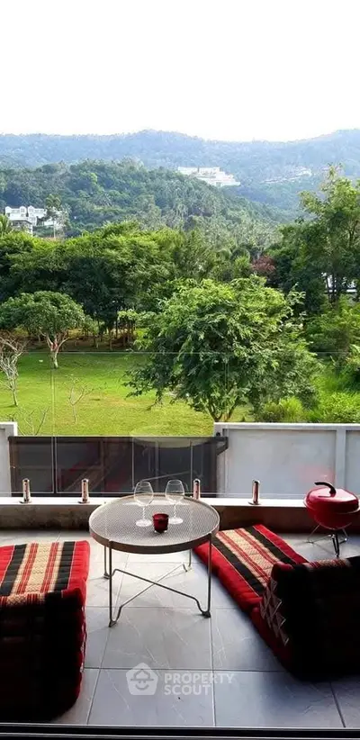 Charming balcony with lush green view, perfect for relaxation and outdoor dining.