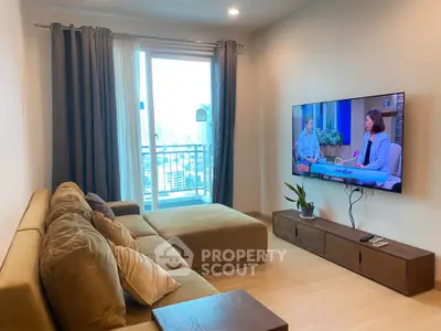 Modern living room with large TV and cozy sofa, featuring a city view balcony.